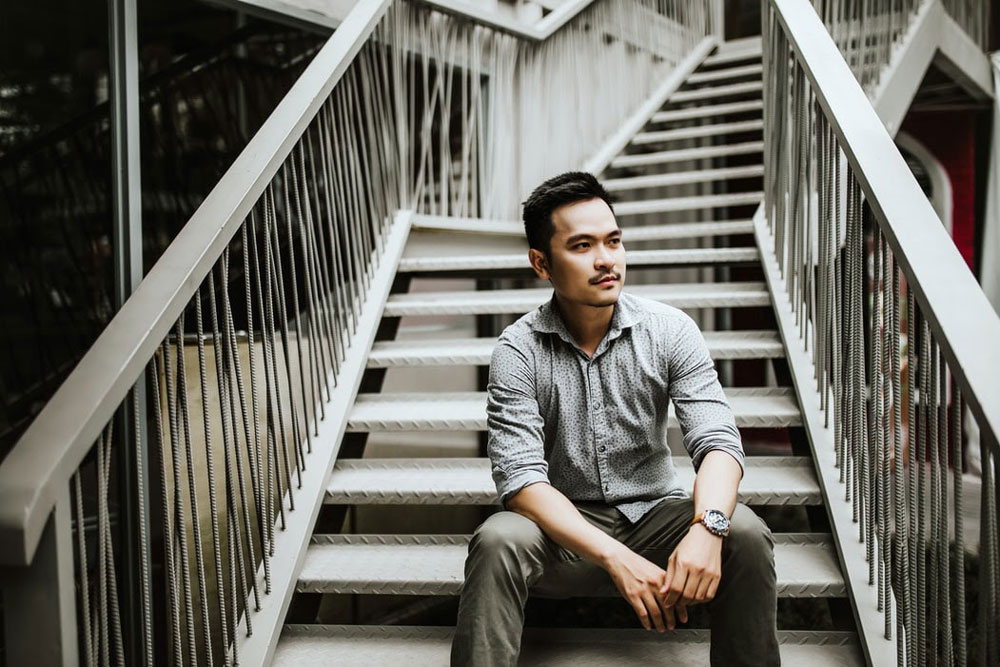 A man sitting on a staircase wearing a casual watch